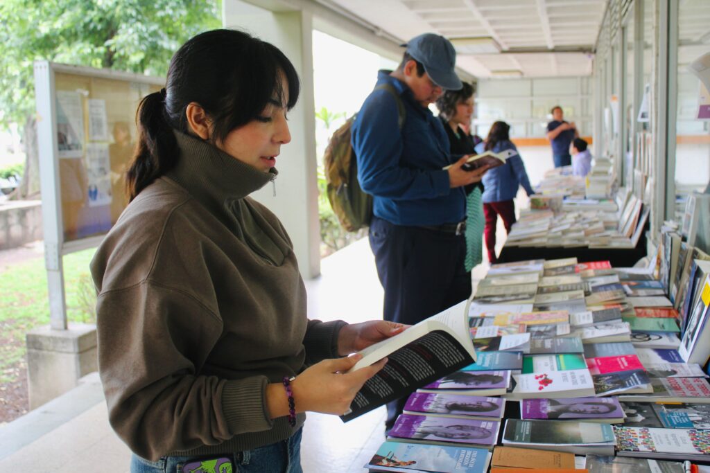 Adults browsing and reading books at an outdoor market in Naucalpan, Mexico.